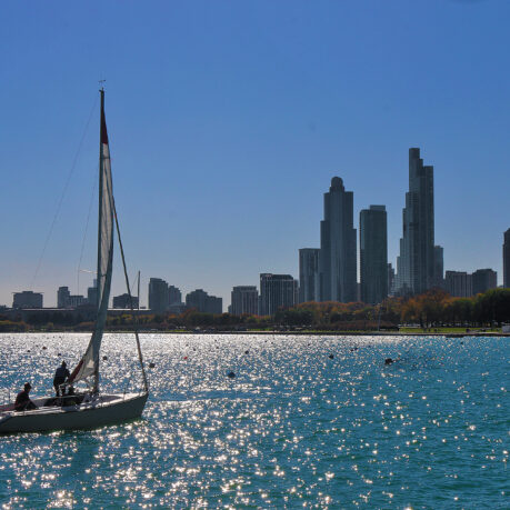 a sailboat on the water with a city in the background