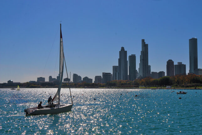 a sailboat on the water with a city in the background