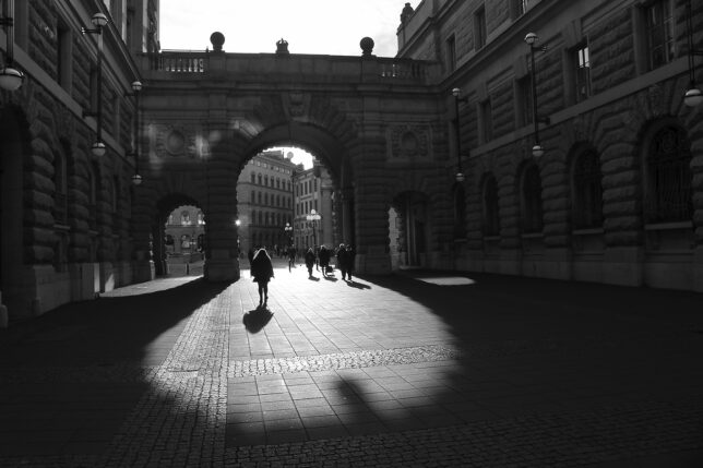 people walking under a stone archway