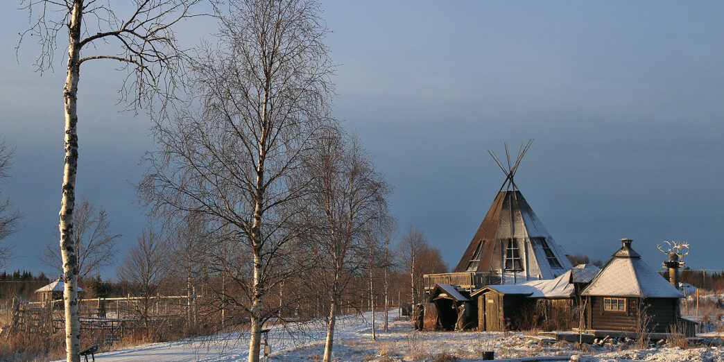 a building with a triangular roof and trees in the snow