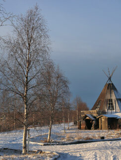 a building with a triangular roof and trees in the snow