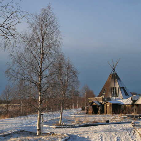a building with a triangular roof and trees in the snow