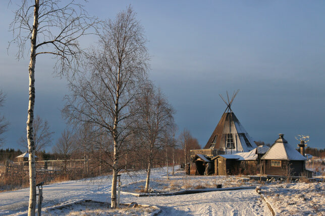 a building with a triangular roof and trees in the snow