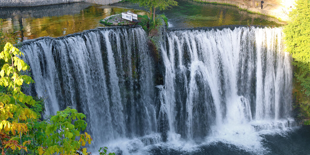 a waterfall with trees and a path