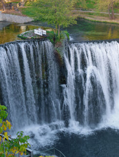 a waterfall with trees and a path