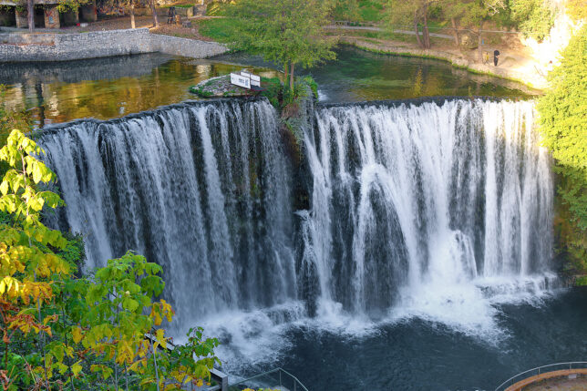 a waterfall with trees and a path