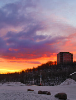 a snowy field with buildings in the background