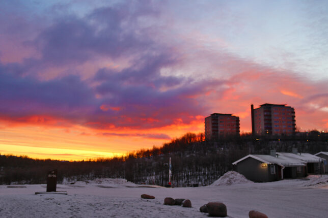 a snowy field with buildings in the background