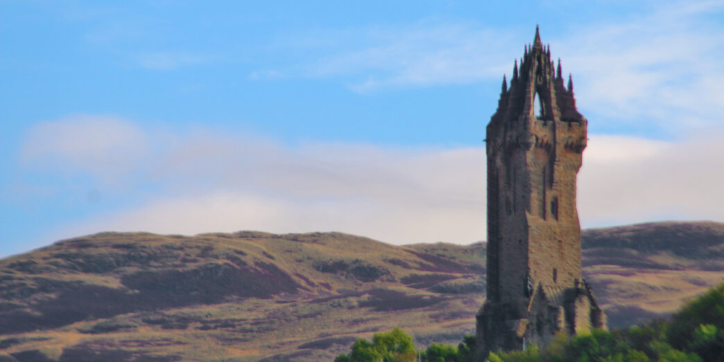 a stone tower with a steeple and trees in the background