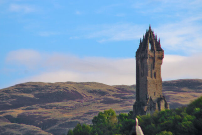 a stone tower with a steeple and trees in the background