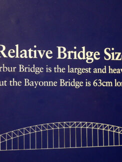 a blue sign with white text and a bridge