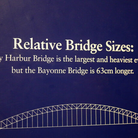 a blue sign with white text and a bridge