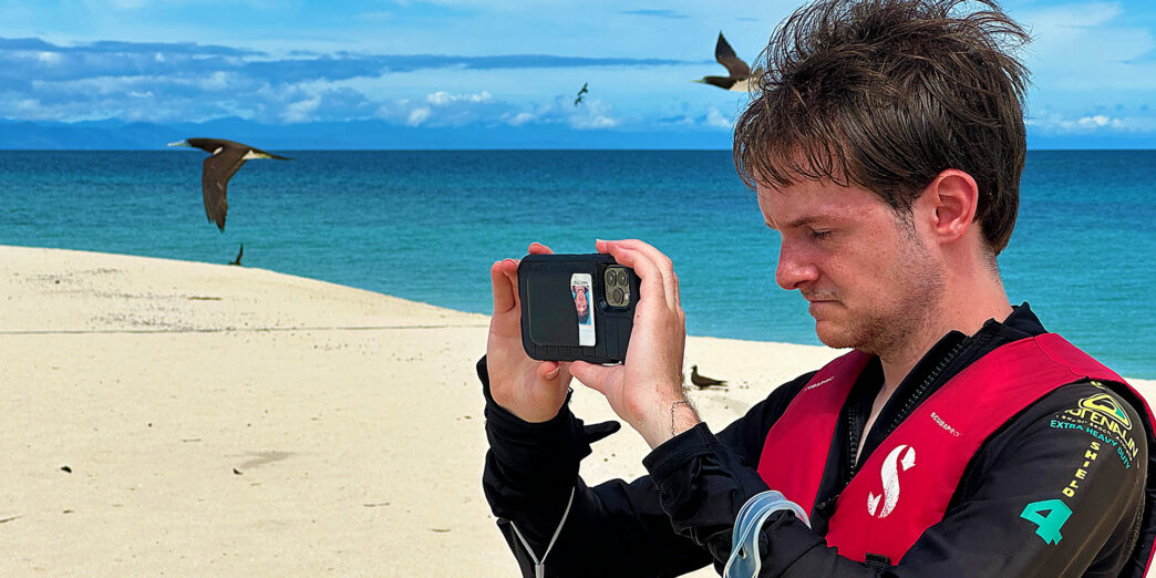 a man taking a picture of a bird on a beach