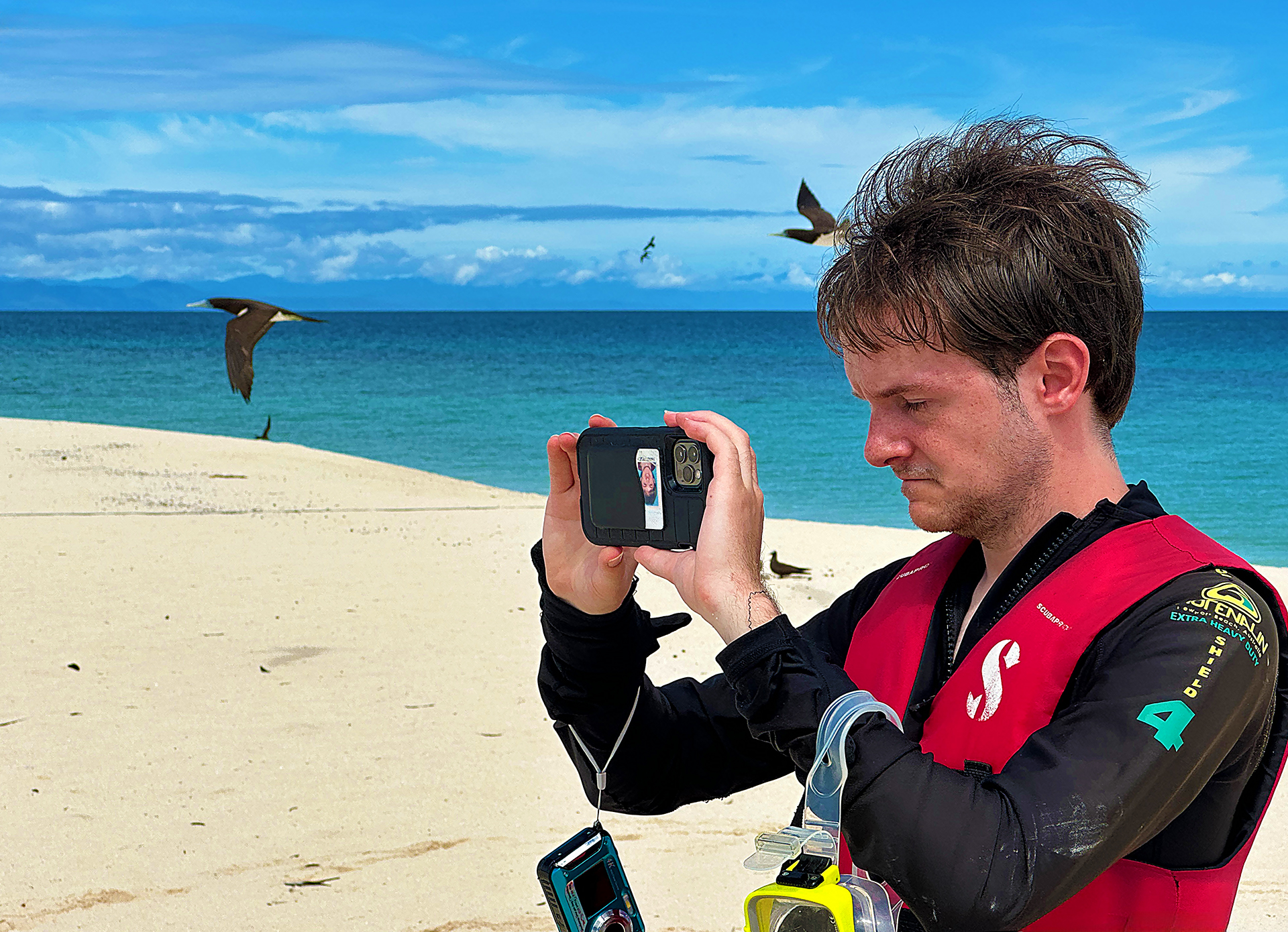 a man taking a picture of a bird on a beach