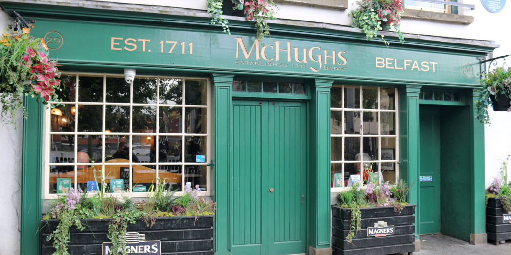 a green store front with flowers in pots