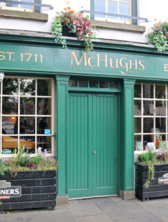 a green store front with flowers in pots