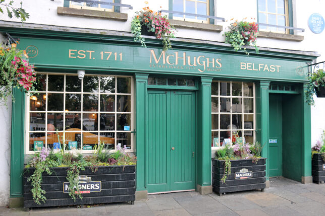a green store front with flowers in pots