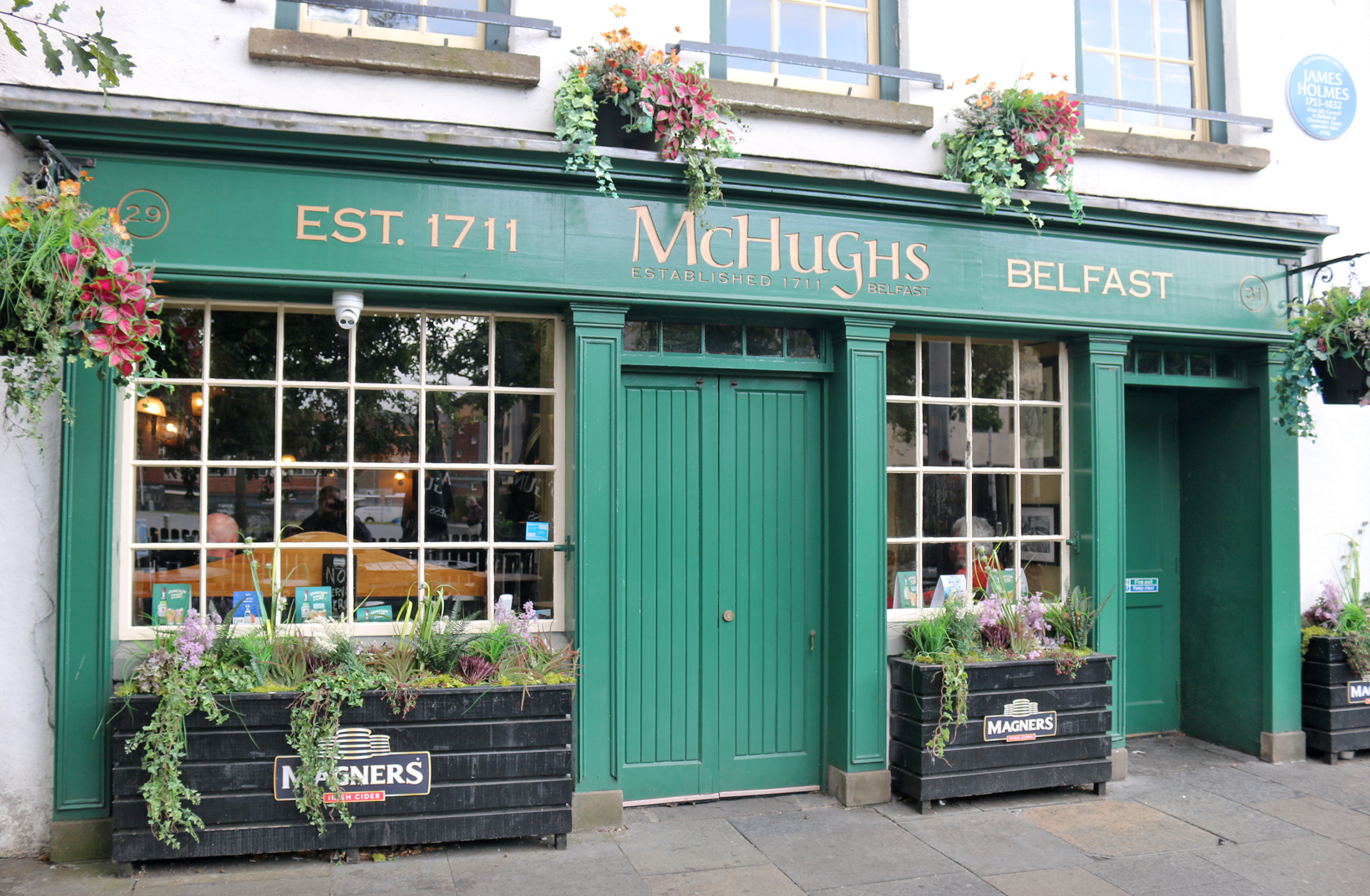 a green store front with flowers in pots