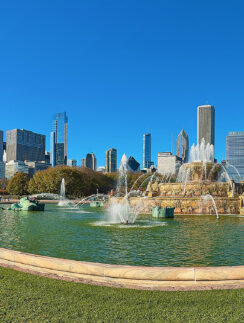 a fountain in a park with a city in the background