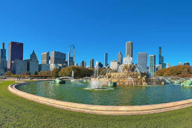 a fountain in a park with a city in the background