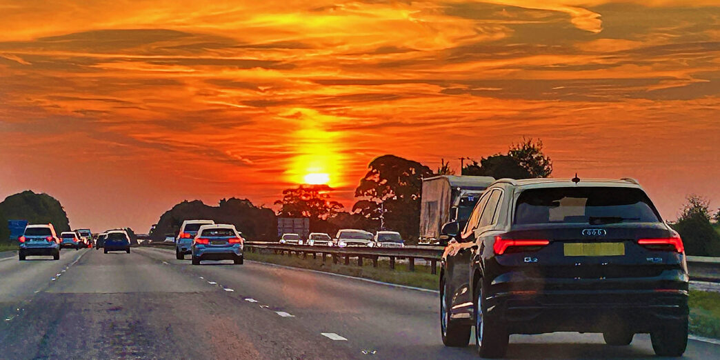 a road with cars on it and a sunset