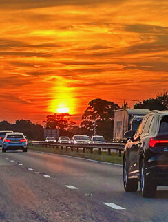 a road with cars on it and a sunset