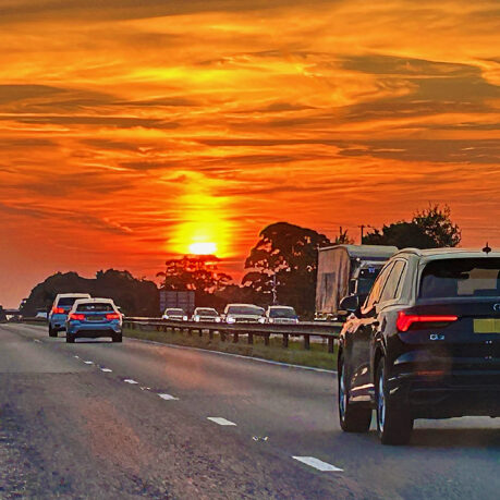 a road with cars on it and a sunset
