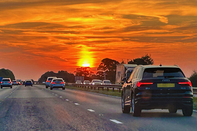 a road with cars on it and a sunset