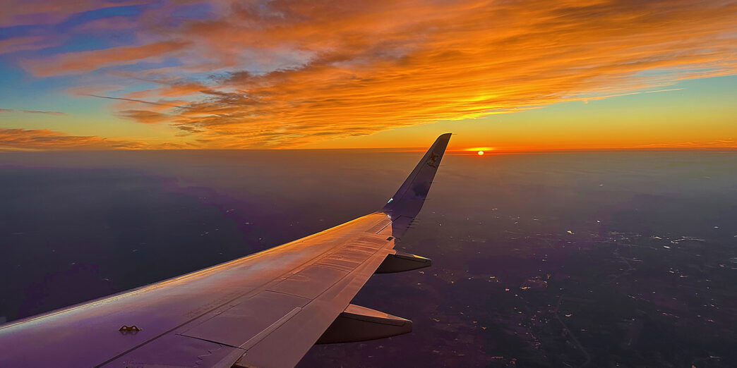 an airplane wing and the sun in the sky