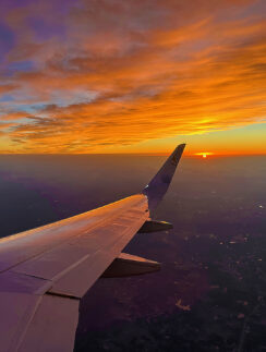 an airplane wing and the sun in the sky