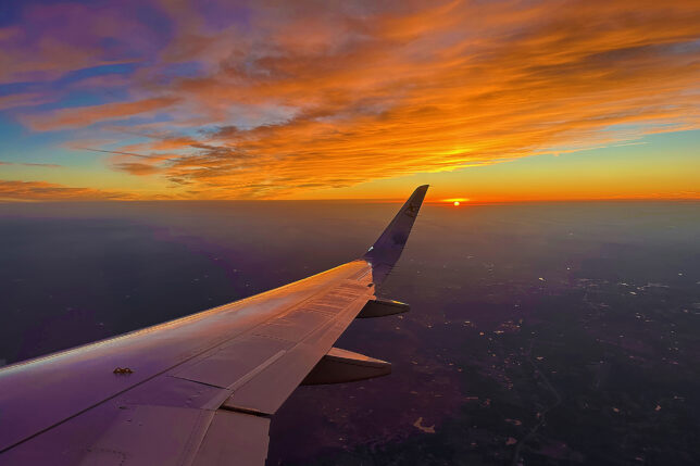 an airplane wing and the sun in the sky