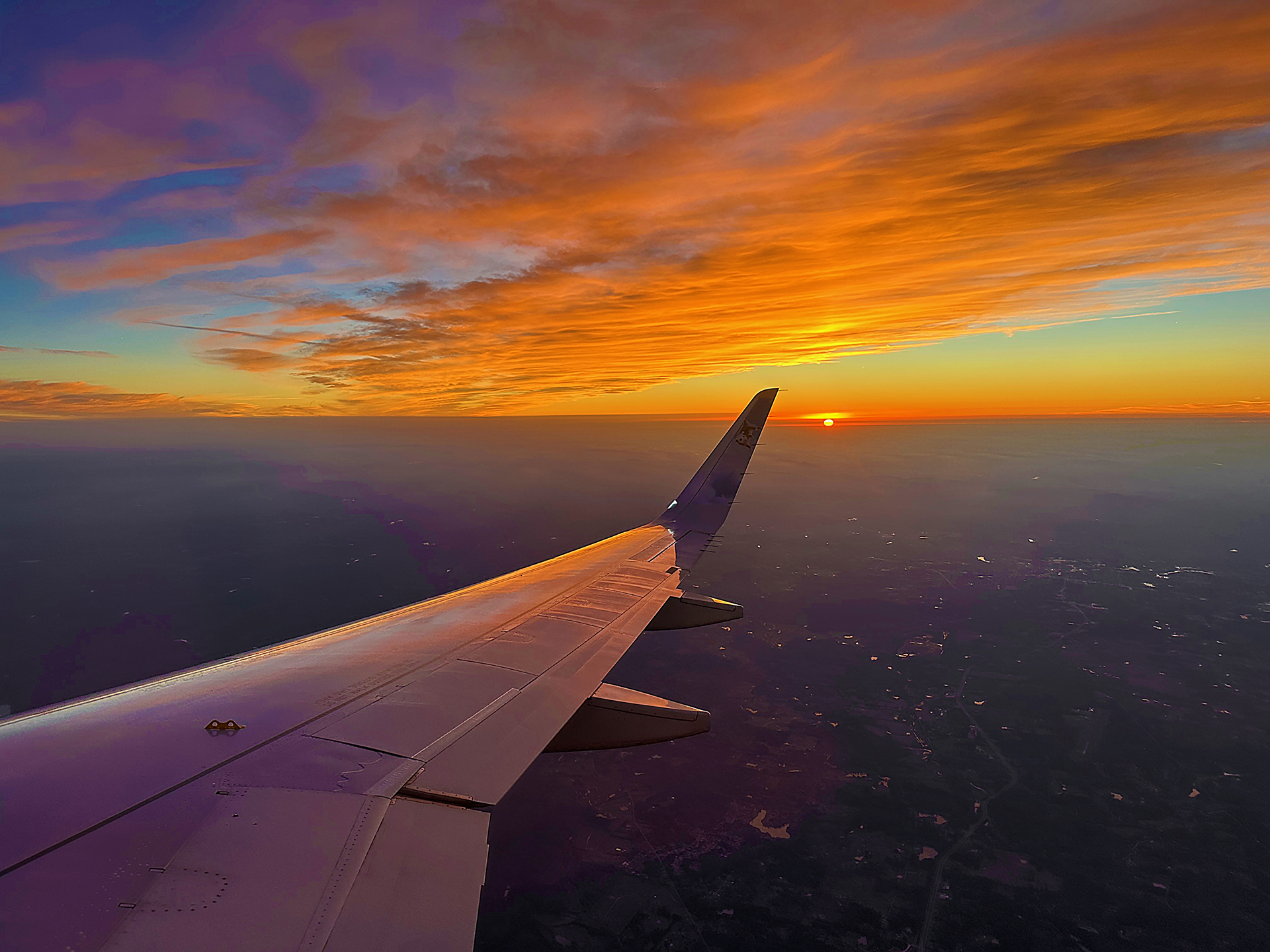 an airplane wing and the sun in the sky