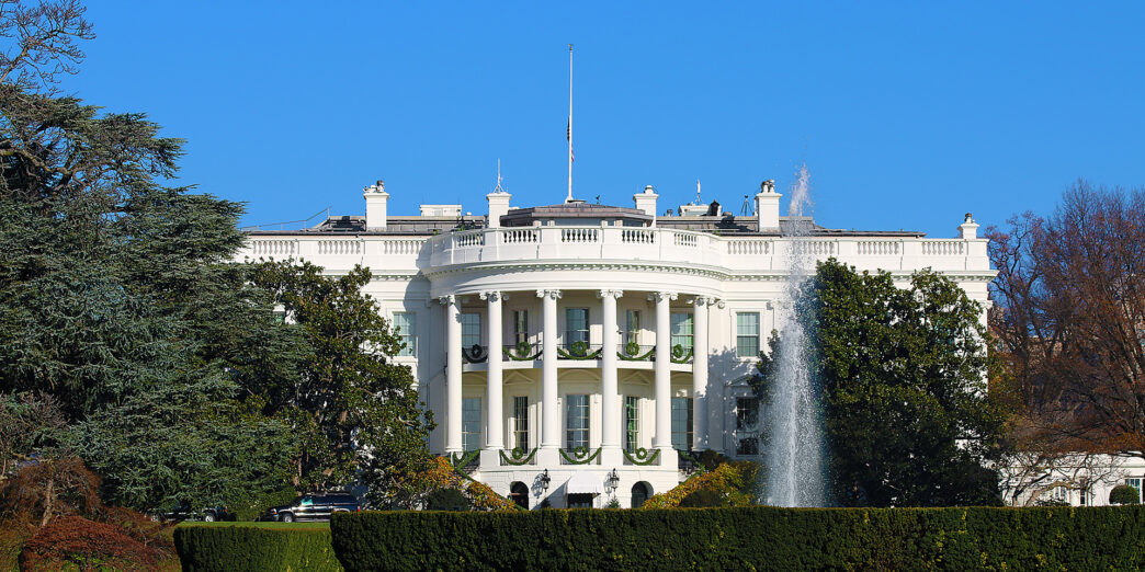 a white building with columns and a fountain in front with White House in the background