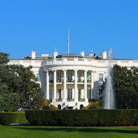 a white building with columns and a fountain in front with White House in the background