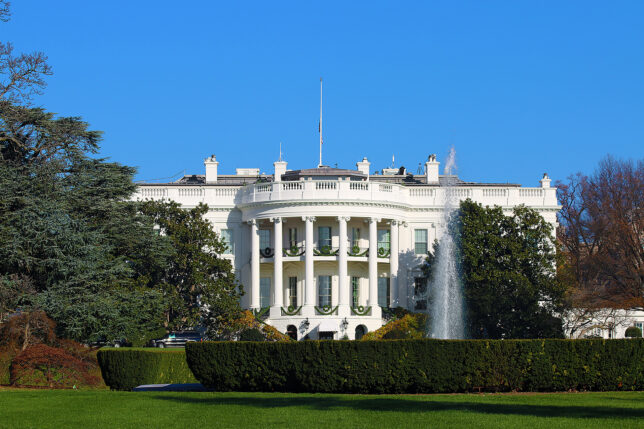 a white building with columns and a fountain in front with White House in the background