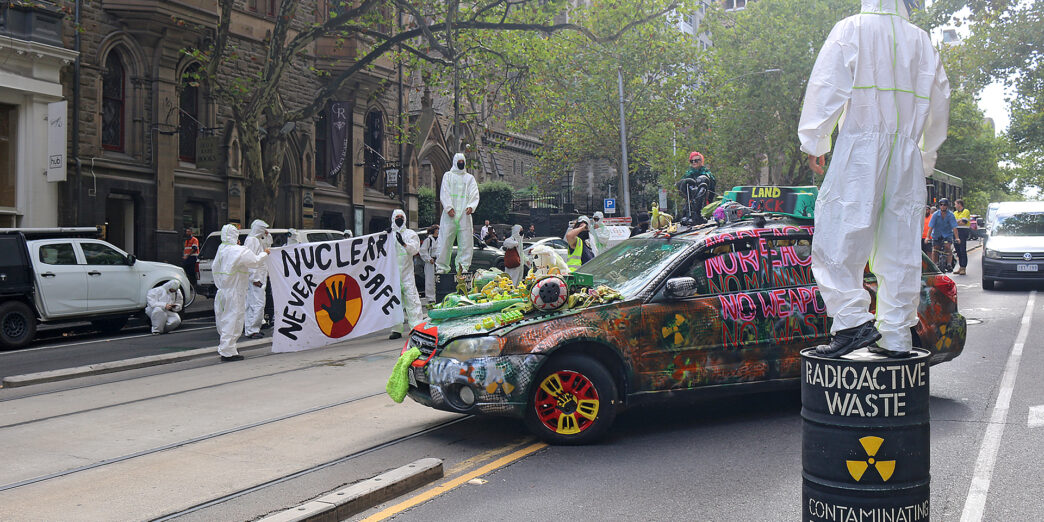 a group of people in white protective suits standing on a street with a car