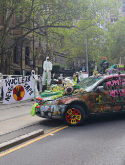 a group of people in white protective suits standing on a street with a car