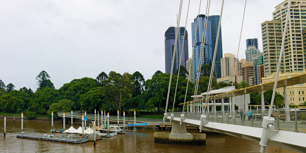 a bridge over a river with a body of water and a city in the background