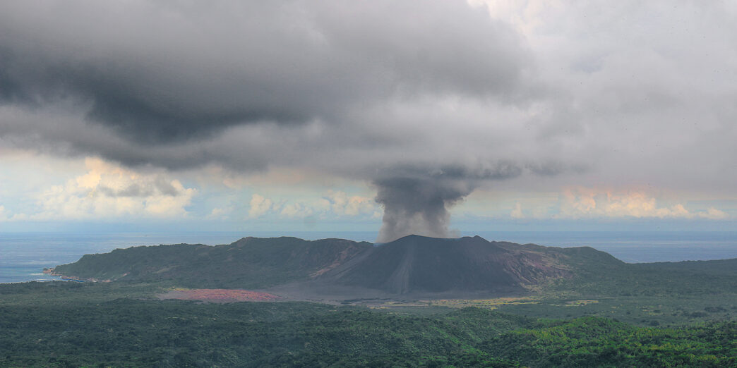a volcano erupting in the middle of a forest
