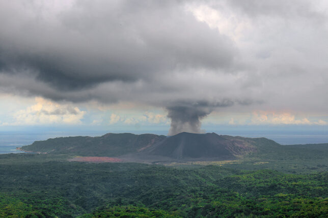 a volcano erupting in the middle of a forest