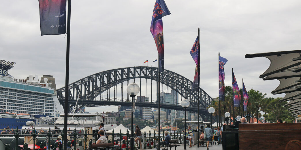 a bridge with flags and people walking on benches
