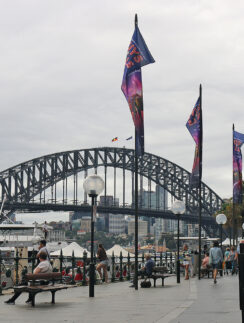 a bridge with flags and people walking on benches