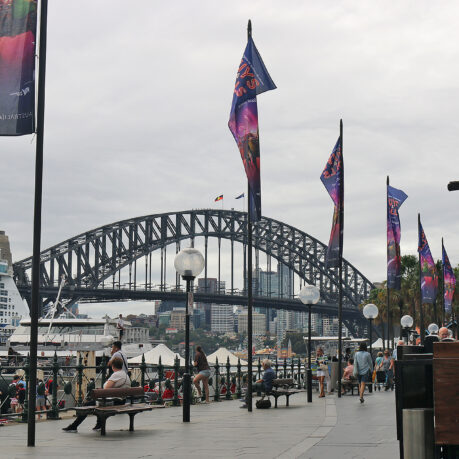 a bridge with flags and people walking on benches