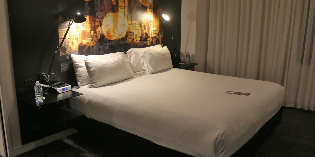 a bed with white sheets and a night stand