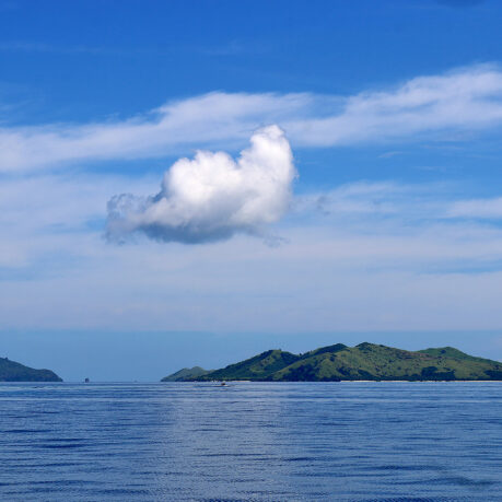 a body of water with a white cloud above it
