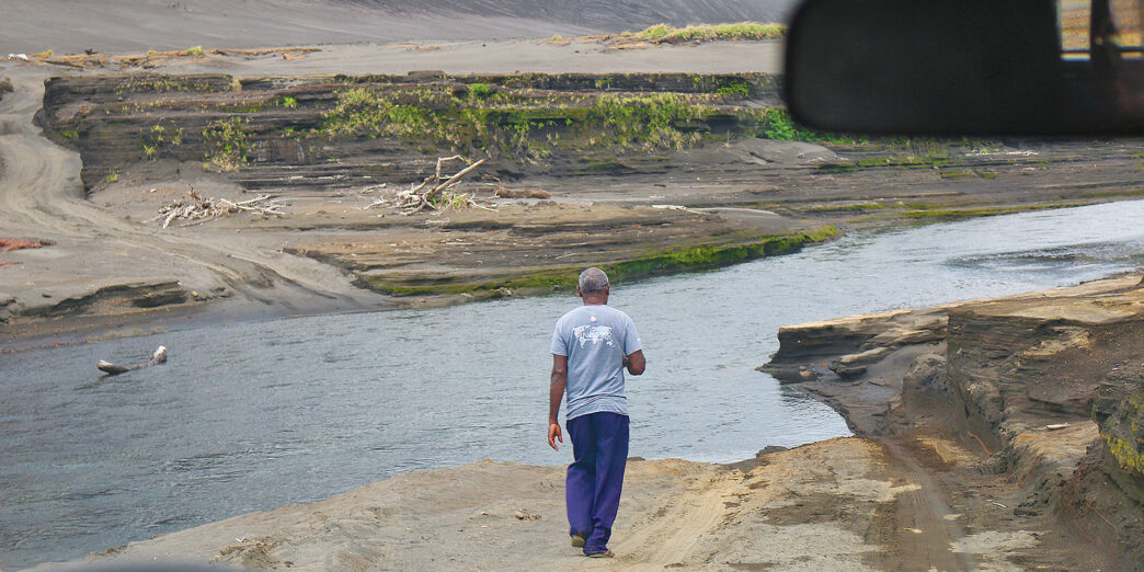 a man walking on a dirt road near water