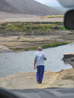 a man walking on a dirt road near water