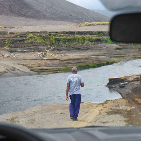 a man walking on a dirt road near water