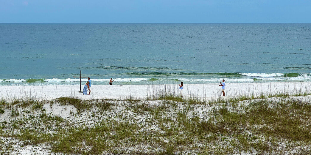 people on a beach with a cross and grass