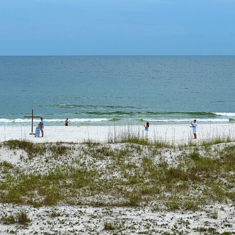 people on a beach with a cross and grass